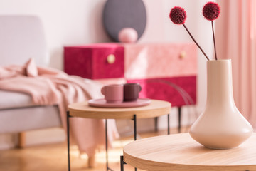 Fancy flower in beige vase on wooden coffee table in fashionable living room