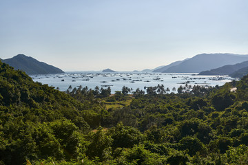 Green hills and sea bay with many floating houses and fishing boats