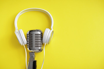 Retro microphone and headphones on color background