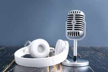 Retro microphone and headphones on table against color background
