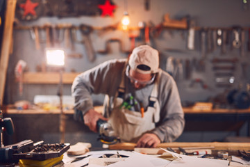 Male carpenter working on old wood in a retro vintage workshop.