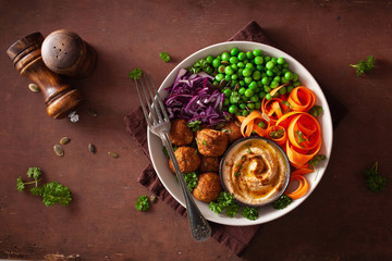 healthy vegan lunch bowl with falafel hummus carrot ribbons cabbage and peas