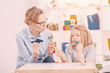 Mother holding toys while playing with concentrated daughter with Asperger syndrome