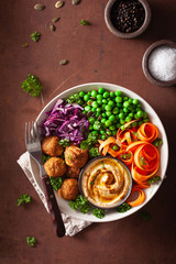 healthy vegan lunch bowl with falafel hummus carrot ribbons cabbage and peas