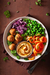 healthy vegan lunch bowl with falafel hummus carrot ribbons cabbage and peas