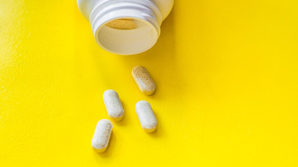 White, green, pink, orange capsules pill spilled out from white plastic bottle container. Global healthcare concept. Antibiotics drug resistance. Antimicrobial capsule pills and thermometer. Pharmaceu