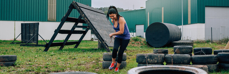 Female participant in an obstacle course dragging wheels seen from behind