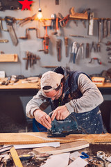 Male carpenter working on old wood in a retro vintage workshop.