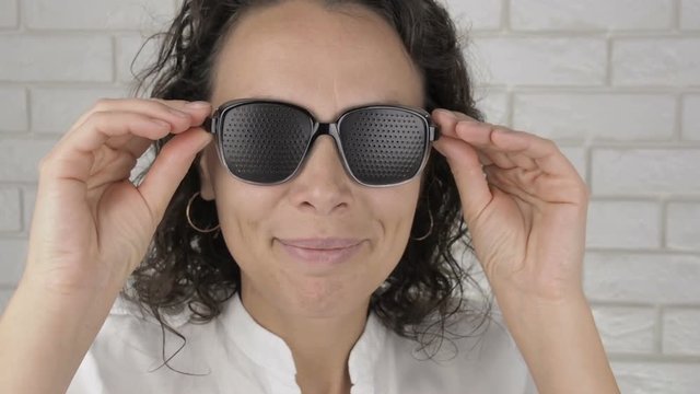 Woman puts on glasses for training vision. Pretty woman in obscura glasses.