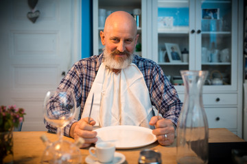 wer kocht ? Mann sitzt vor leerem Teller am Tisch