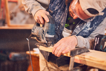 Male carpenter working on old wood in a retro vintage workshop.