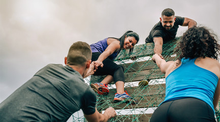 Group of participants in an obstacle course climbing a net - Powered by Adobe