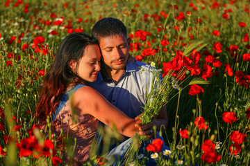 happy man and woman hugging in a field of poppies.