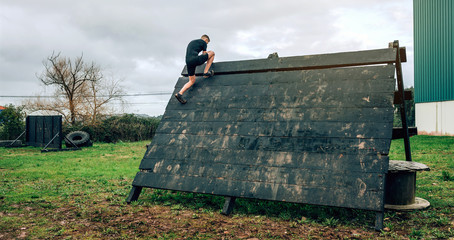 Male participant in an obstacle course climbing a pyramid obstacle