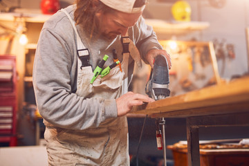 Male carpenter working on old wood in a retro vintage workshop.