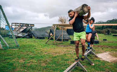 Participants in an obstacle course carrying trunks outdoors