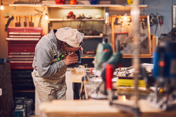 Male carpenter working on old wood in a retro vintage workshop.