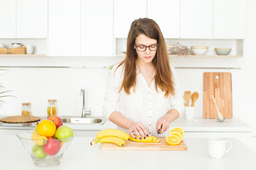 Woman preparing healthy fruit meal in her white eco kitchen