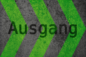 Eine Wand aus Beton hat gruene aufgebrachte Pfeile. Deutscher Text: Ausgang.  Ideal als Hintergrund...