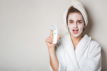 Surprised brunette girl posing with moisturizing cream mask and face cleaner. Empty space