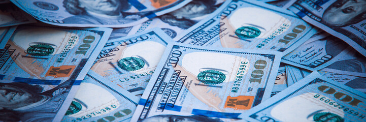 Background from dollars. Notes of one hundred American dollars are scattered across the background.