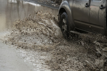 Fototapeta na wymiar Poor road condotions - car wheel in melting show puddle.