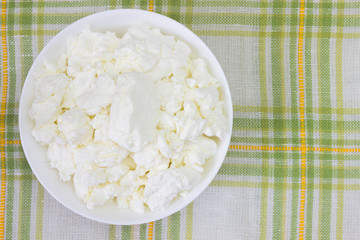 Fresh natural cottage cheese in a white ceramic bowl. Organic eco healthy meal, dairy product. Top view, overhead photo. Place for text, copyspase.