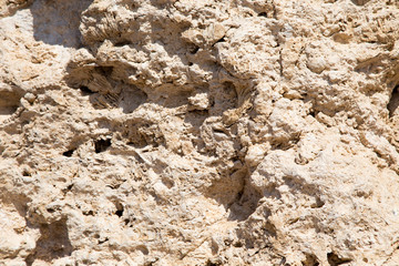 Vintage mud wall in the desert made with beach rocks and coral stones. Texture of stone old wall, old dry coral of brown color. Natural background.