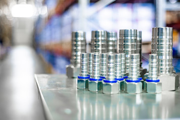 Metal hydraulic fittings stands on the silver table in the warehouse