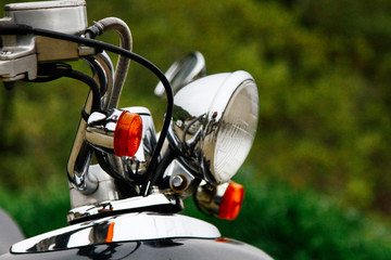 Closeup of a steering wheel and headlights of a vintage scooter