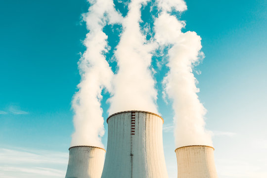 A Power plant with white smoke over it's chimneys