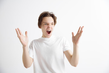 Wow. Attractive male half-length front portrait on gray studio backgroud. Young emotional surprised man standing with open mouth. Human emotions, facial expression concept