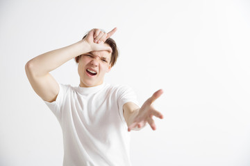 Losers go home. Portrait of happy guy showing loser sign over forehead and smiling in cause of...