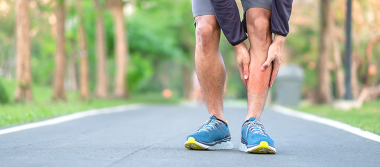 Young fitness man holding his sports leg injury. muscle painful during training. Asian runner having calf ache and problem after running and exercise outside morning. sport and healthy concepts © Jo Panuwat D