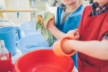 Two kids washing dishes. Montessori engaging educational activities concept. Children cleaning...