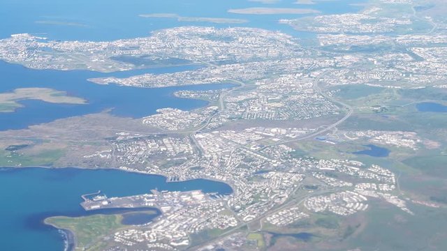 Keflavik, Iceland international airport with aerial high angle view of Reykjavik city from airplane window above slow motion moving panning 