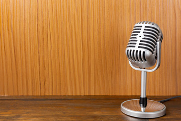 The vintage microphone close up image on wood background.