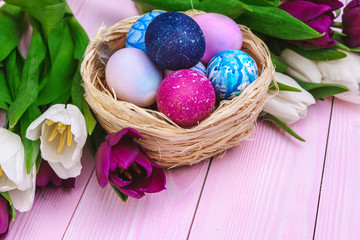 Easter eggs in a nest and tulips on wooden planks