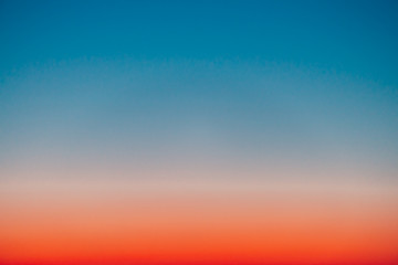 Predawn clear sky with red horizon and blue atmosphere. Smooth orange blue gradient of dawn sky....