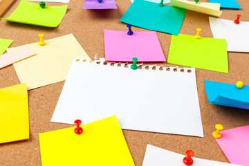 Cork board with several colorful blank notes with pins