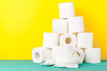 Toilet paper rolls stacked against yellow paper background