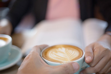 Hand Women and man put a Latte arts coffe hot coffee on wooden table.barista love art concept.
