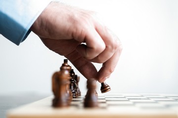 hand of businessman moving chess figure in competition success play. strategy, management or leadership concept.