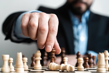 hand of businessman moving chess figure in competition success play. strategy, management or leadership concept.
