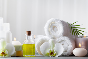 Obraz na płótnie Canvas Spa, beauty treatment and wellness background with massage oil, orchid flowers, towels, cosmetic products and burning candles.