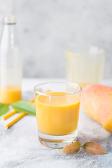 Tropical Mango smoothie in a glass and fresh mango on a light background. Mango shake. Tropical fruit concept.