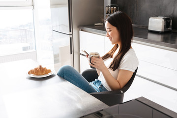 Smiling young asian woman using mobile phone