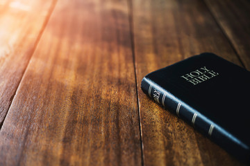 holy bible on wooden table background with soft morning sun light