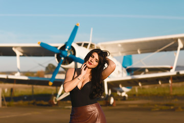 Airplane and woman at sunset. Traveler woman standing at airplane. Woman and landing commercial plane in the evening. Lifestyle