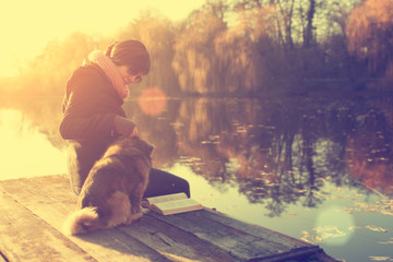 Woman with a dog in sunset at a lake